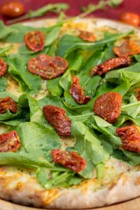 Close-up Photo of Basil Pizza in a Round Wooden Tray